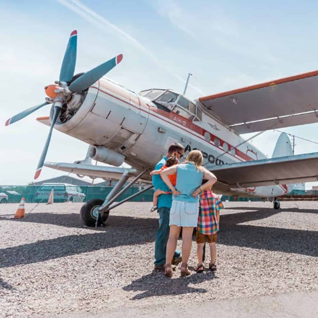 A family stands in front of a vintage plane at the Chico Air Museum