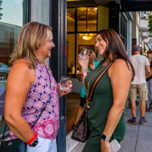 Two women laughing and smiling while drinking wine outside of the Hotel Diamond during the Downtown Chico Art and Wine Walk