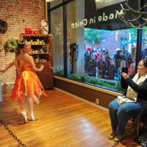 A young ballerina dances in a store window and people are watching from the outside during Chico's Christmas Preview