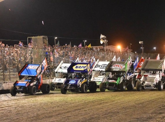 A row of stock cars racing on the dirt track at Silver Dollar Fairgrounds during the Gold Cup Race of Champions