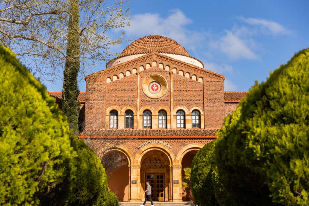 A male college student walks in front of Kendall Hall at California State University, Chico