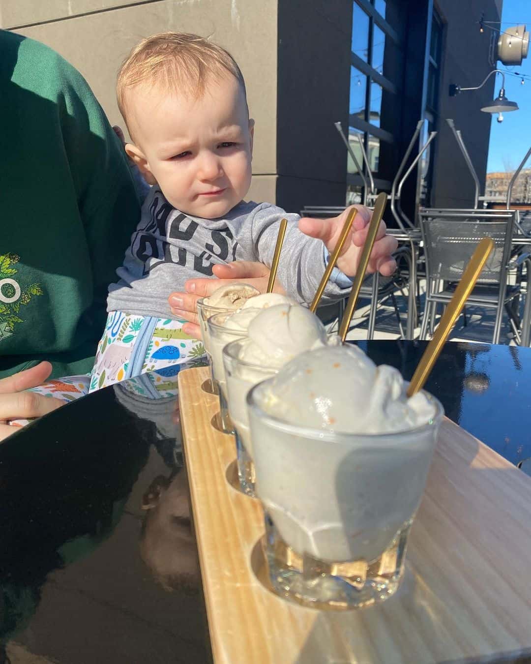 A baby reaches for a flight of four ice cream flavors at Savor Ice Cream
