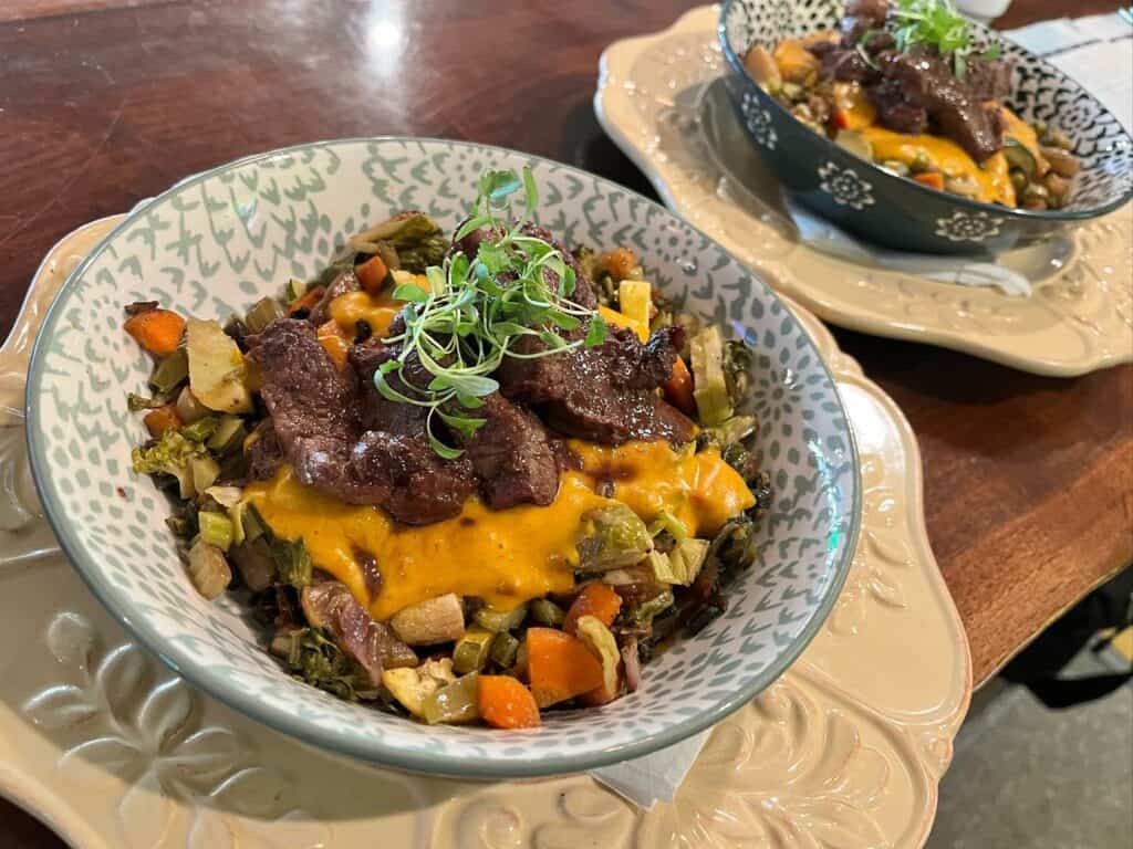 Two bowls of a mixed vegetable dish with steak on top from Lili's Brazilian Bistro