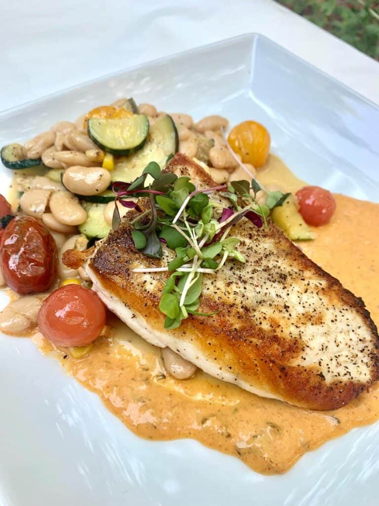 Close-up of pan seared fish over a bed of sauce and white beans from Red Tavern