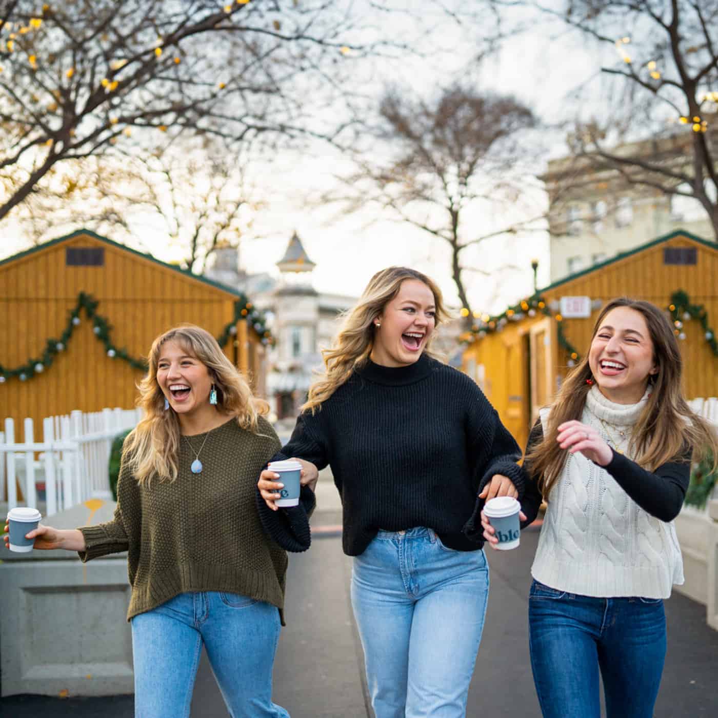 Three women linking arms and laughing near the Chico Ice Rink