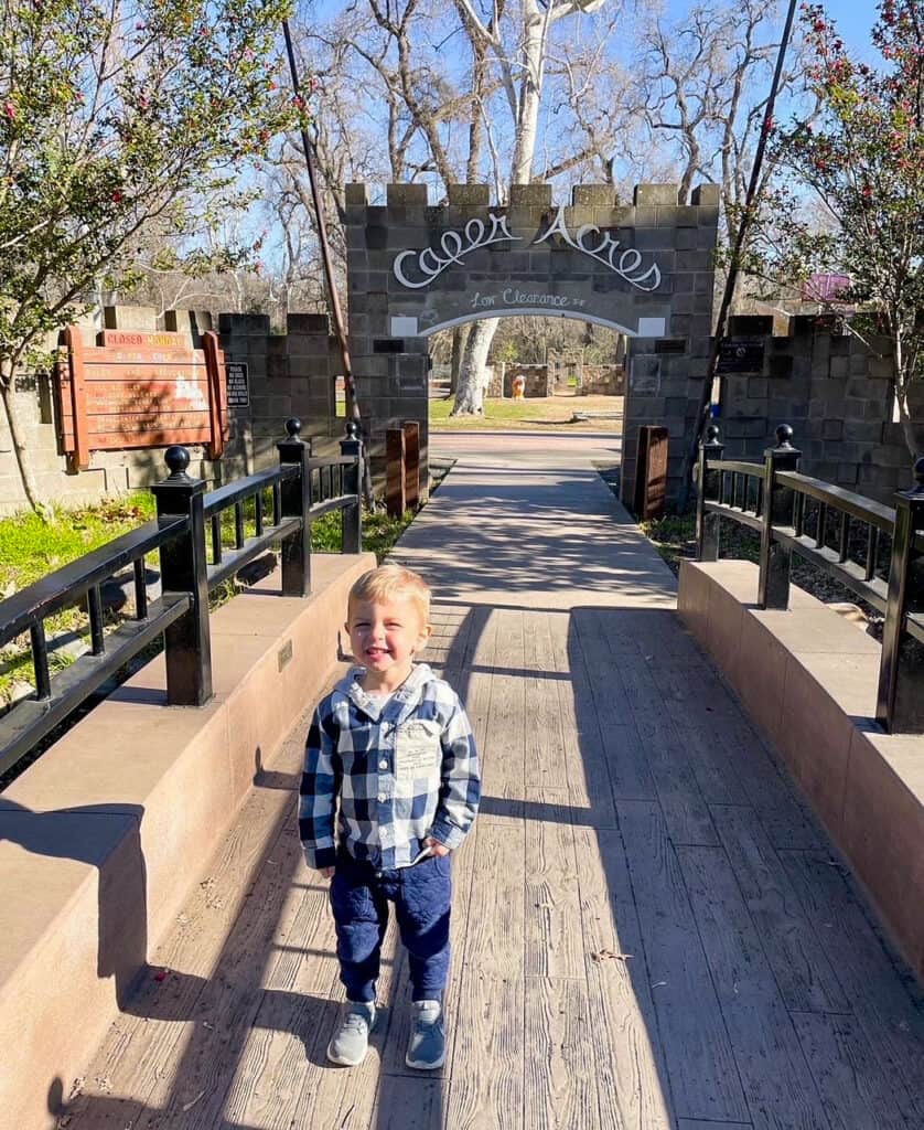 A toddler boy standing in front of the Caper Acres entrance