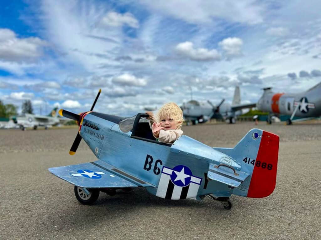 A kid sitting in a toy airplane