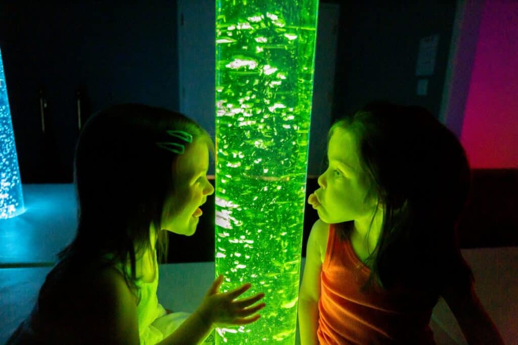 Two girls in front of a glowing tube