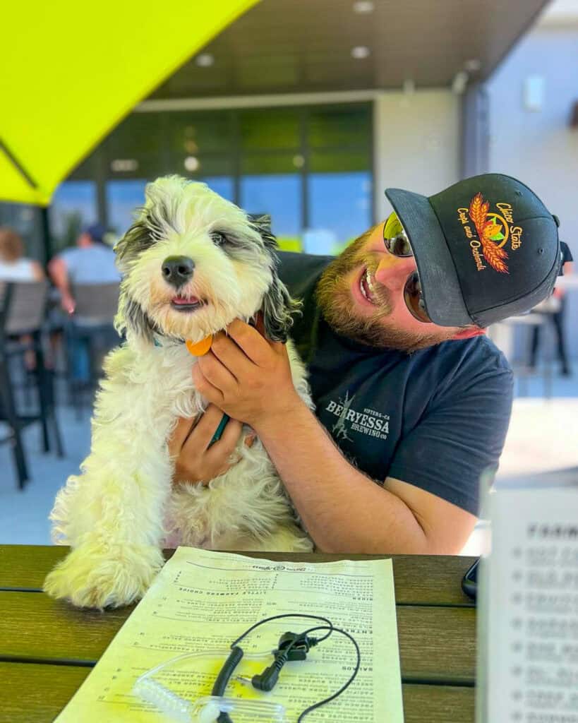 A happy man and his dog dining outside