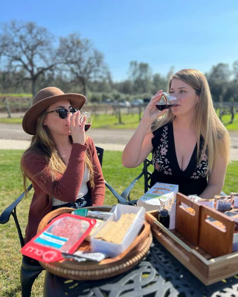 Two women taking a sip from wine glasses