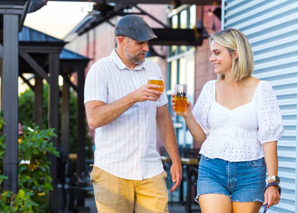 A couple drinking beer clinks their glasses together