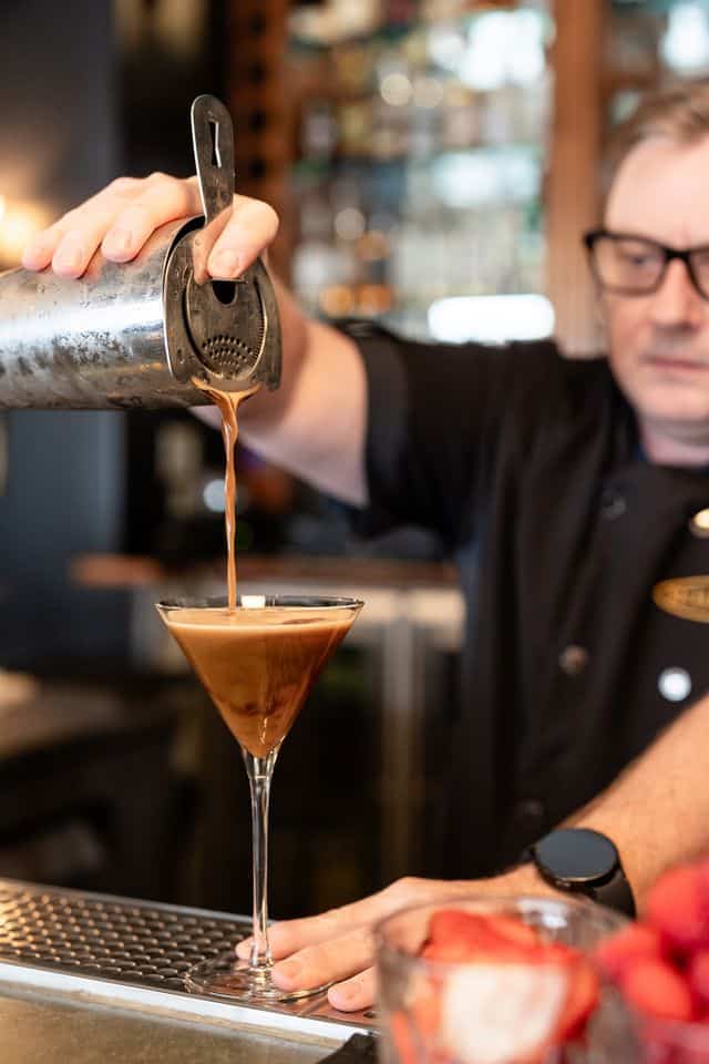 A bartending pouring an espresso martini