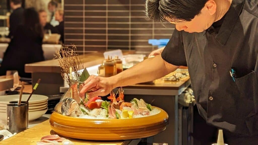 A chef puts the finishing touches on a large sushi platter