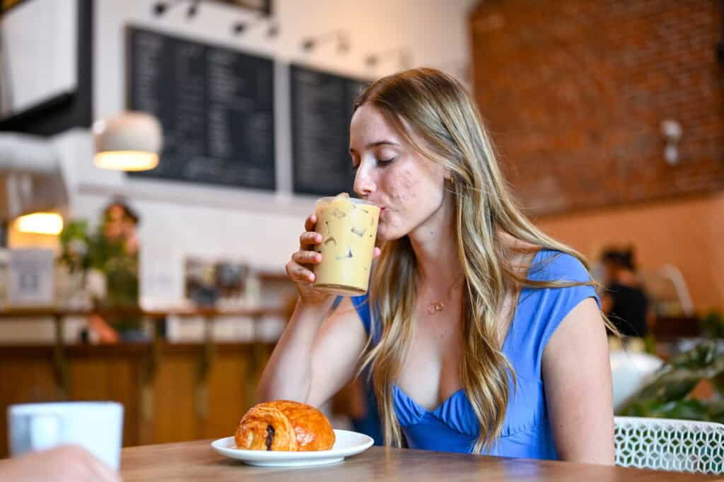 A woman takes a sip of an iced latte
