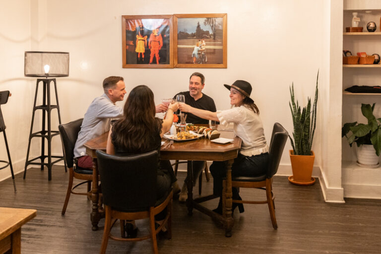 Four friends clinking their drinks in cheers over dinner